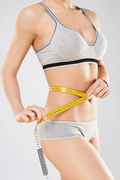 istock Holding yellow measuring tape on waist 689485404