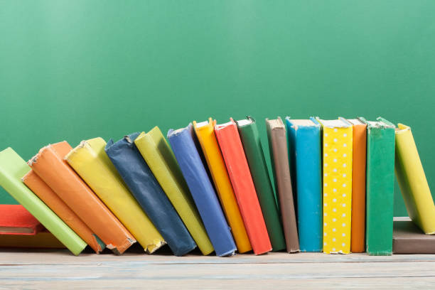 Book stacking. Open hardback books on wooden table and green background. Back to school. Copy space for ad text