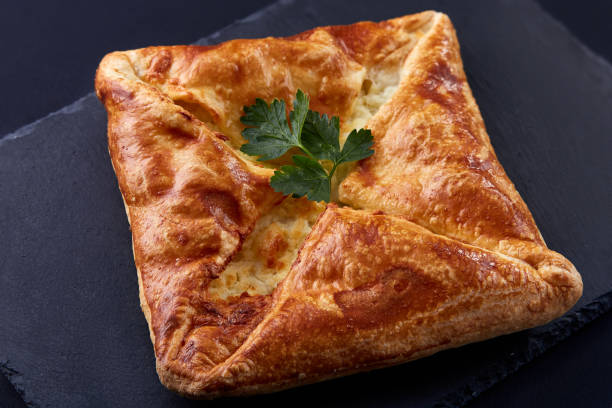 istock Homemade cheese puff pastries with parsley on black background 689496866