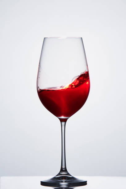istock Red wine in a crystal pure wineglass showing waves against light background. 689496932