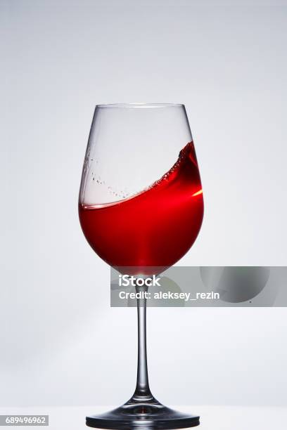 Elegant Pure Wineglass With Wave Of Brightly Red Wine Standing Against Light Background With Reflection In Down Stock Photo - Download Image Now