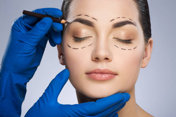 Plastic surgeon drawing dashed lines above eyebrow stock photo