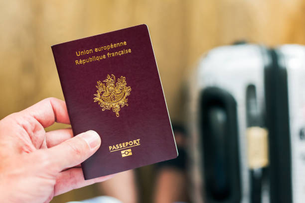 Hand holding a french - european passport with luggage in the ba stock photo