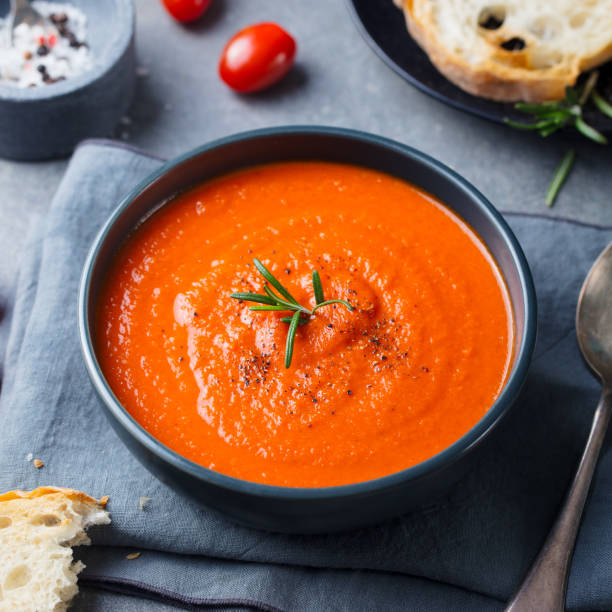 istock Tomato soup in a black bowl on grey stone background. 689537408