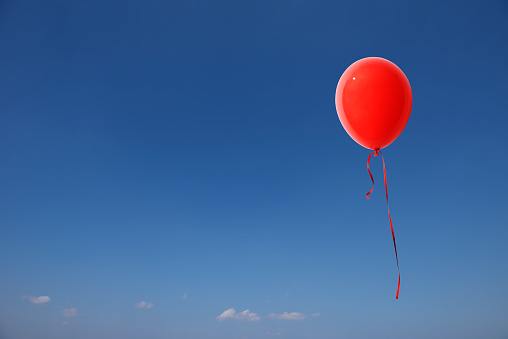 Red balloon floating in a clear sky with copy space.