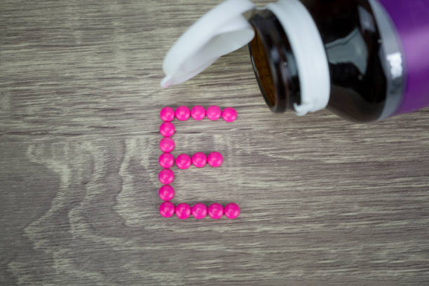 istock Pink pills forming shape to E alphabet on wood background 689544398