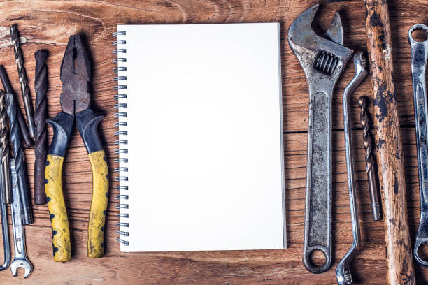 istock Various tools and the blank notebook on a wooden background 689548550