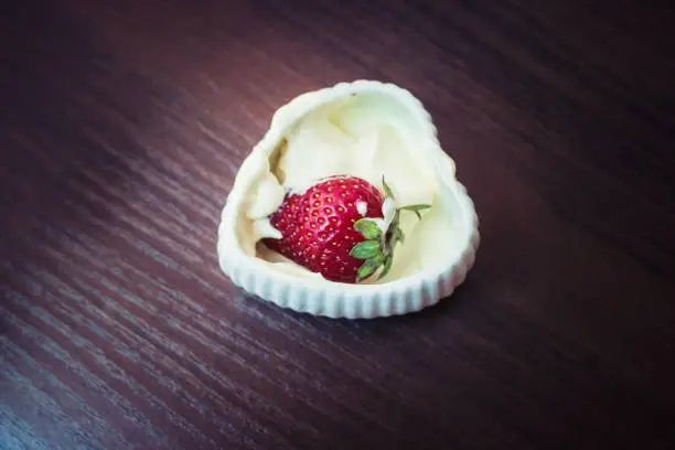 Strawberries in a plate with cream in the shape of heart