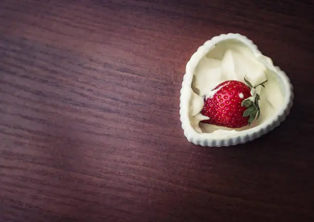 Strawberries in a plate with cream in the shape of heart