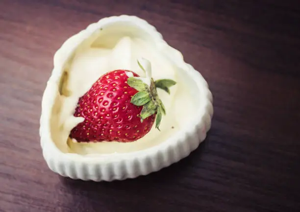 Strawberries in a plate with cream in the shape of heart