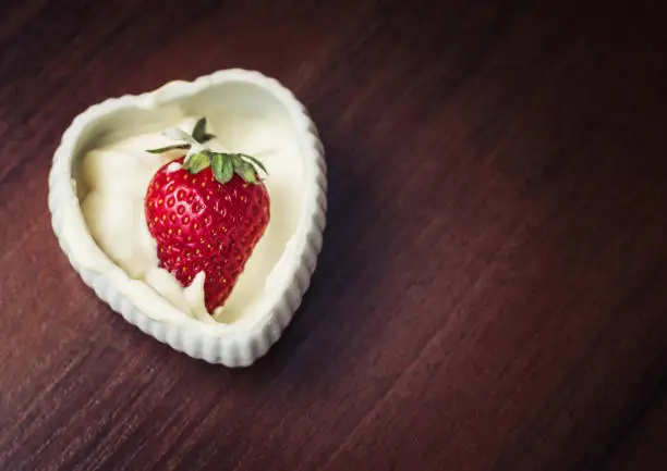 Strawberries in a plate with cream in the shape of heart