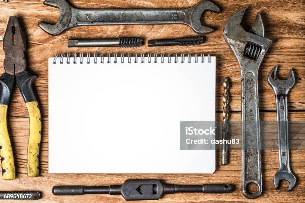 Various Tools And The Blank Notebook On A Wooden Background Stock Photo - Download Image Now