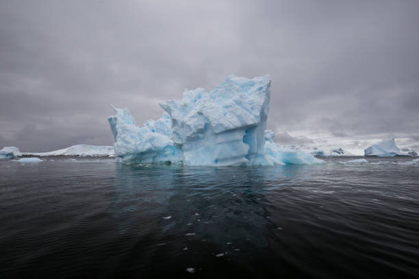 曇りの日に南極大陸沖海岸のエンタープライズ島沖美しい青い色氷ベルク フロート - extreme terrain eroded snow landscape ストックフォトと画像