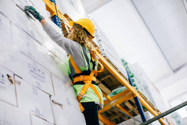 Young female manual worker hanging on a climbing rope in warehouse