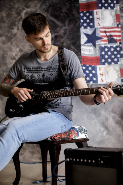 istock Young handsome musician playing electric guitar on dark background 689564618