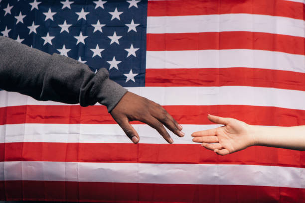 istock Black and white hands on american flag background 689572270
