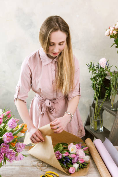 istock Woman have pack festive bouquet in wrapping paper. 689576048