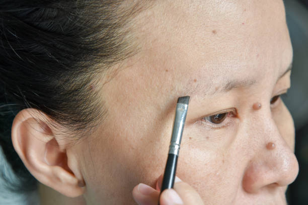 asian woman applying makeup with eyebrow brush Close up of asian woman applying makeup with eyebrow brush asian eyebrows stock pictures, royalty-free photos & images