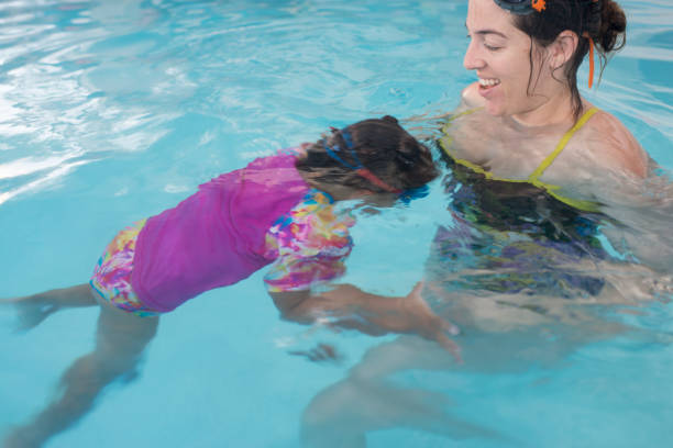 istock Baby swimming lessons - learning how to float and hold the breath. 689585902