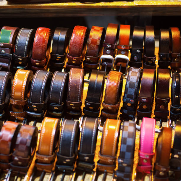Offered belts for men placed on a table on night market in Bangkok. Seen on corner market at street Kaset Nawamin. Table of market stall. Belts have different colores and styles.