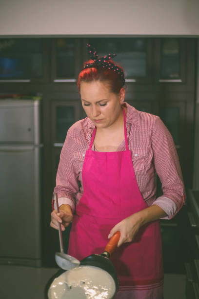 istock girl pours a ladle dough for pancakes. Cooking pancakes at home. 689598708