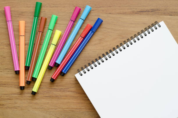 istock Wooden desk table with notebook and color pens. Top view with copy space, flat lay. 689604256