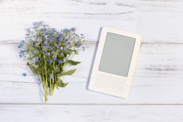 White ebook and forget me not bouquet on a white rustic wooden background