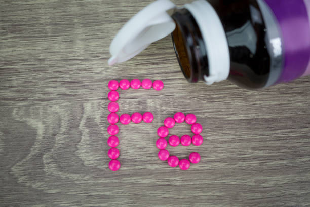 istock Pink pills forming shape to Fe alphabet on wood background 689610192