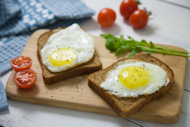 istock Healthy Breakfast: scrambled eggs on slices of whole-grain bread with arugula and tomatoes on a wooden Board 689630708