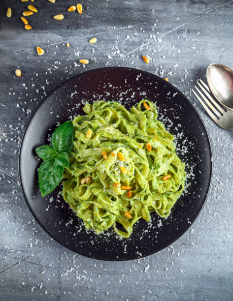 istock Tagliatelle pasta with pesto sauce, pine nuts and parmesan on black plate. 689630836