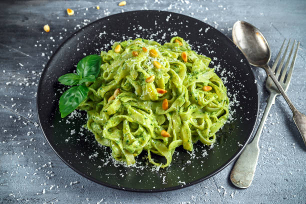 istock Tagliatelle pasta with pesto sauce, pine nuts and parmesan on black plate. 689632936