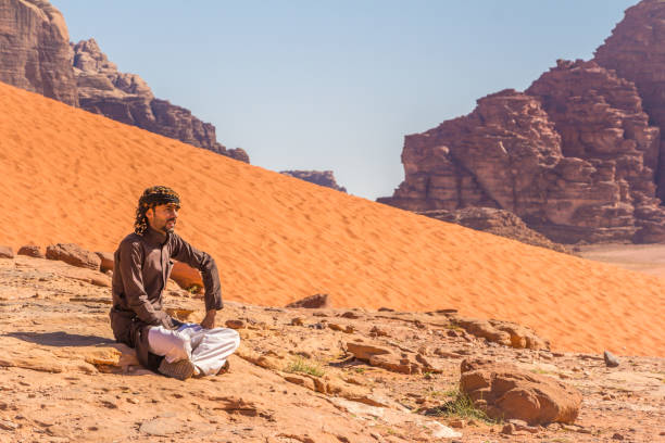 homem de beduínos está descansando em uma rocha no deserto de wadi rum na jordânia - aramaic - fotografias e filmes do acervo