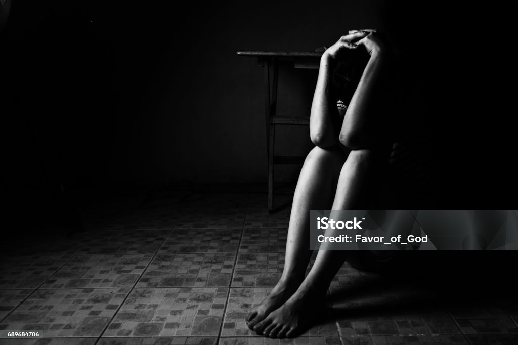 a woman sitting on ground with arm around lower head, sexual violence , sexual abuse, human trafficking concept a woman sitting on ground with arm around lower head, sexual violence , sexual abuse, human trafficking concept with shadow edge in white tone Sexual Assault Stock Photo