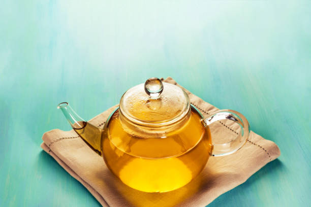 istock Teapot full of tea on teal texture with copyspace 689684906