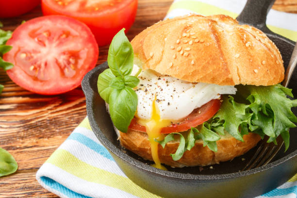 istock Breakfast. Bun with sesame seeds, poached egg,  tomato and greens. Selective focus 689691454