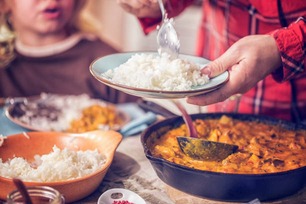 Eating Delicous Homemade Chicken Curry Dish with Rice Young family eating delicious homemade chicken curry dish with basmati rice. hot rice  stock pictures, royalty-free photos & images