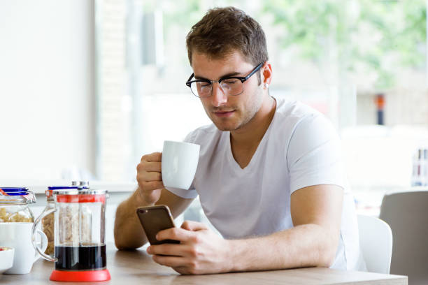 istock Handsome young man using his mobile phone while enjoying the breakfast in the kitchen. 689737768