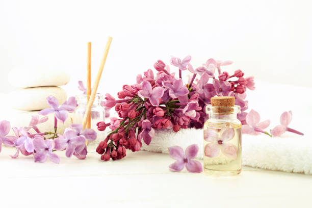 botella de aceite esencial tapada con flor interior en extracto, frescos tonos lilas, blancos - aromatic oil burner fotografías e imágenes de stock