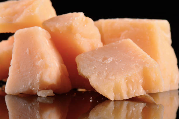 istock Parmesan cheese on a black glossy table with reflection. Parmesan cheese isolated on black background. 689752376