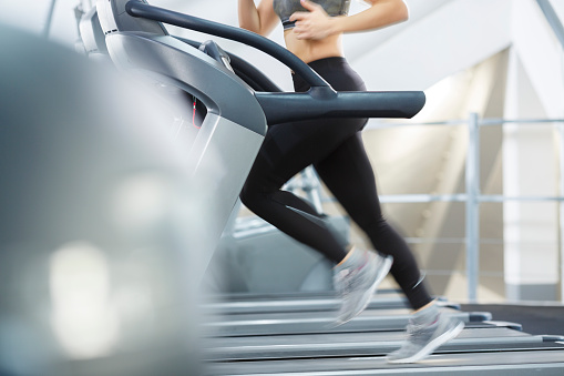 Treadmill workout background Close up Legs in motion  At the gym  Healthy woman running on treadmill Sports Training  Sporting Women