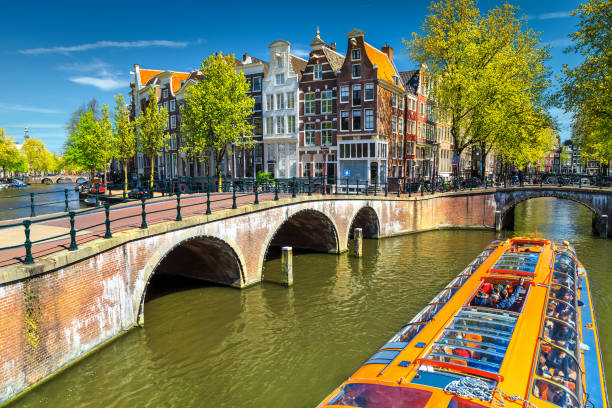 typical amsterdam canals with bridges and colorful boat, netherlands, europe - amstel river amsterdam architecture bridge imagens e fotografias de stock