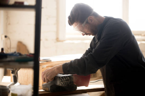 istock Serious skilled carpenter working using sander for grinding wood, indoors 689766004