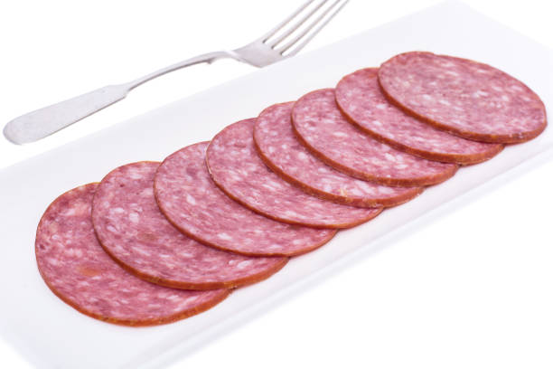 Slices of salami on white plate. Studio Photo