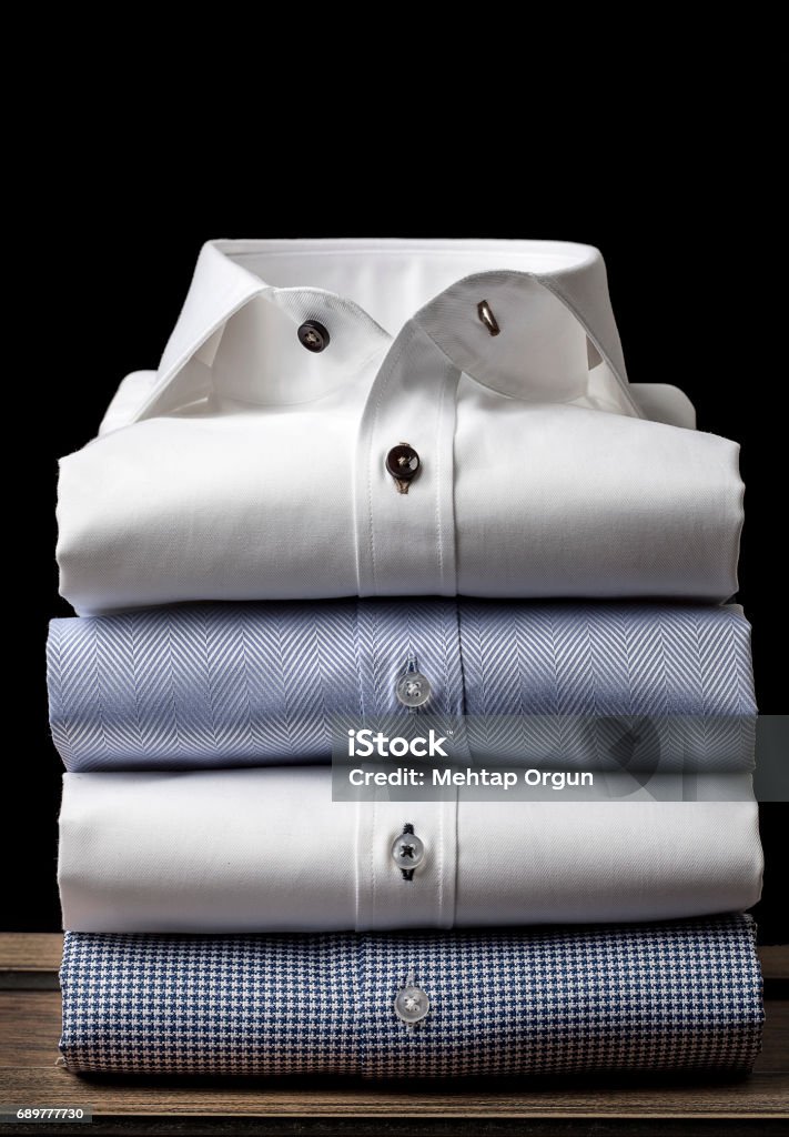 Folded Men's Shirts Folded and ironed mens shirts on the wooden floor, behind the black background Shirt Stock Photo