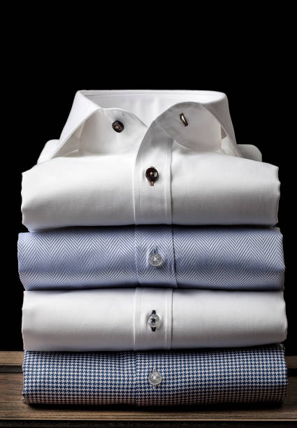 Folded Men's Shirts Folded and ironed mens shirts on the wooden floor, behind the black background businesswear stock pictures, royalty-free photos & images