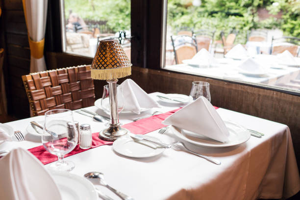 istock table setting for a lovey dinner. Empty glasses set in restaurant. Part of interior. napkins, plates, and cutlery. 689778028