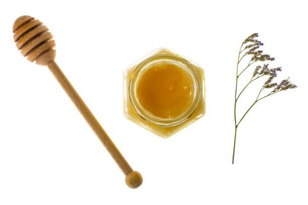 istock Spoon and honey in glass jar on white background 689784698