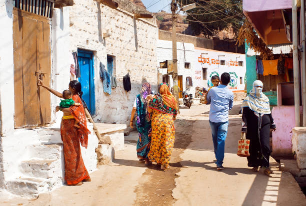 Many people on narrow street with brick rural houses of small town in Karnataka state Badami, India - February 8, 2017: Many people walking on narrow street with brick rural houses of small town in Karnataka state on February 8, 2017. Population of Karnataka is 62,000,000 people urgency mother working father stock pictures, royalty-free photos & images