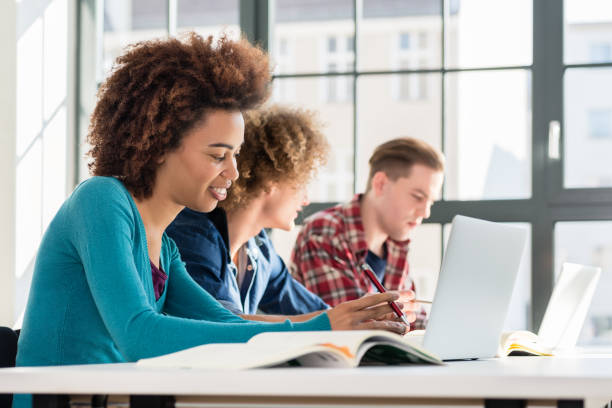 istock Close-up on student holding a pen over a book while studying a t 689793230