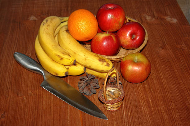 A white plate on a white background with fruit consisting of a yellow and green banana and red apple on the plate